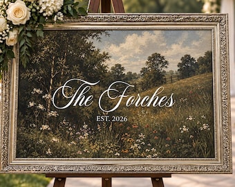 Puede incluir: Un letrero rectangular en un marco metálico con una pintura de paisaje de un campo de hierba con árboles y el texto blanco The Forches EST. 2026. El letrero está decorado con un racimo de rosas blancas y follaje verde en la esquina superior.