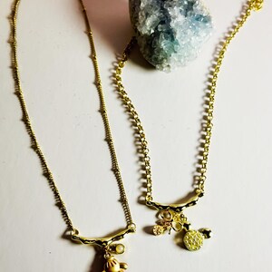 Gold Mickey Mouse glove, and pearl Minnie Mouse charm with a bow necklace. 16in