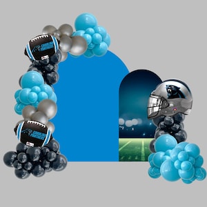 Può includere: Un arco e un'esposizione di palloncini festosi con palloni da football e un casco dei Carolina Panthers. L'arco comprende palloncini neri, argentati e blu. I palloni da football hanno il logo dei Carolina Panthers. Il casco è argentato con il logo della squadra.