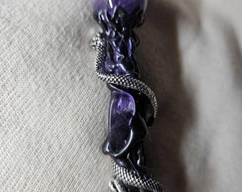 May include: A dark purple wand with a spherical amethyst crystal at the top. A silver-colored snake wraps around the wand's body. The wand has a black base and intricate carved details.