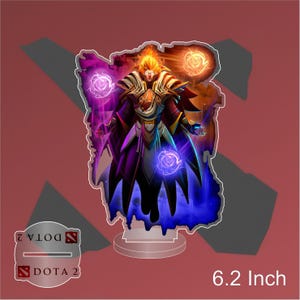 Op de afbeelding: Een 15,7 cm hoge acrylstandaard met een Dota 2-personage met paarse, blauwe en oranje gloedeffecten. Het personage draagt een paarse en gouden mantel en heeft een gouden kroon.