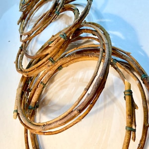 May include: A set of brown twig wreaths, tied together with green rubber bands. The wreaths are arranged in a spiral pattern, creating a unique and rustic look.