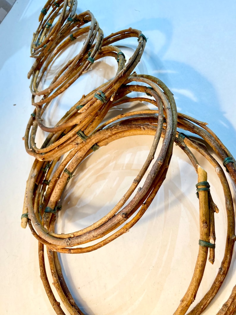 May include: A set of brown twig wreaths, tied together with green rubber bands. The wreaths are arranged in a spiral pattern, creating a unique and rustic look.