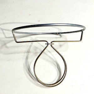 May include: A silver lampshade clip on ring with a brass adjustable holder. The holder has a double loop design that fits over a lightbulb.