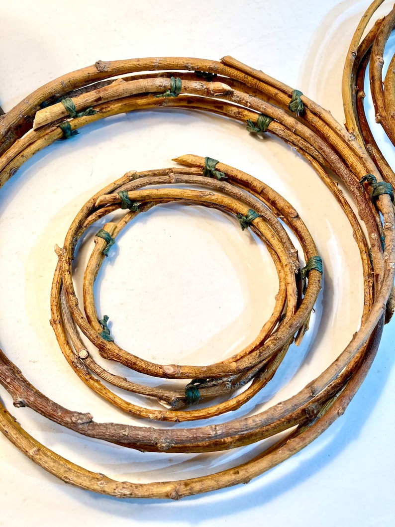 May include: A wreath made of brown twigs tied together with green twine. The wreath is made of several layers of twigs, creating a thick and textured look.