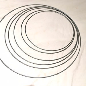 May include: A set of six silver metal hoops of varying sizes. The hoops are arranged in a concentric circle pattern.