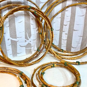 May include: A set of five brown twig wreaths, each tied together with green twine. The wreaths are arranged in a semi-circle on a white background.