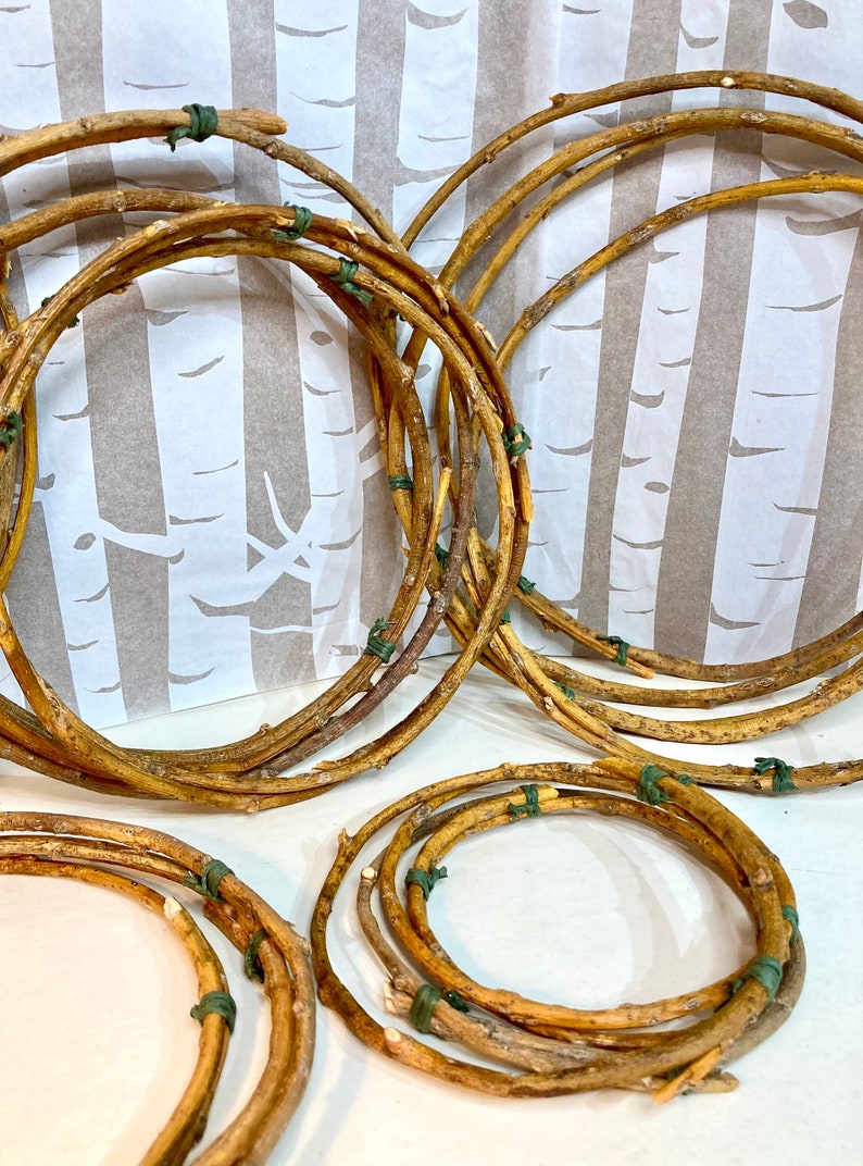 May include: A set of five brown twig wreaths, each tied together with green twine. The wreaths are arranged in a semi-circle on a white background.