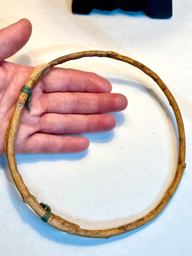 May include: A brown twig hoop with green rubber bands securing the ends. The hoop is about 10 inches in diameter.