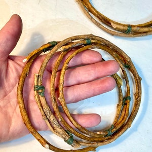 May include: A set of five brown twig wreaths tied together with green string. The wreaths are arranged in a circle and are about 10 inches in diameter.