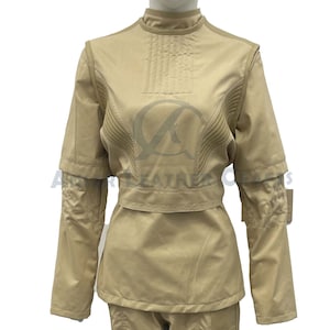 May include: A tan long-sleeved jumpsuit with a high collar and a belt. The jumpsuit has a quilted design on the chest and sleeves.