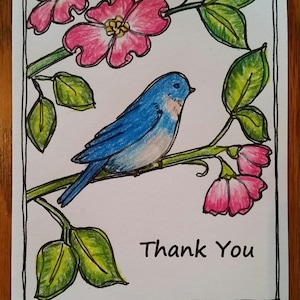 May include: A bluebird perched on a branch with pink flowers and green leaves. The background is white with a black border. The text "Thank You" is written below the bird.