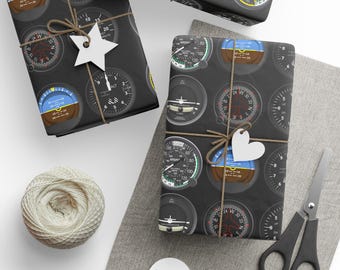 May include: Wrapping paper featuring a repeating pattern of black and white aircraft cockpit instrument gauges, including altimeters and attitude indicators. The paper is tied with brown twine and includes white star and heart-shaped gift tags.