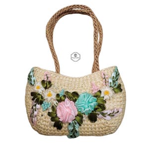 Pu&ograve; includere: Borsa a mano in paglia intrecciata con manico intrecciato. La borsa &egrave; decorata con fiori di stoffa rosa, blu e bianchi e foglie verdi. La borsa ha la scritta "KULTURA".