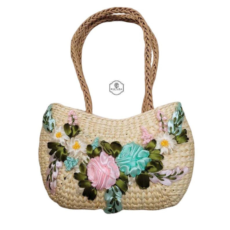 Pu&ograve; includere: Borsa a mano in paglia intrecciata con manico intrecciato. La borsa &egrave; decorata con fiori di stoffa rosa, blu e bianchi e foglie verdi. La borsa ha la scritta "KULTURA".