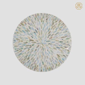 Puede incluir: Plato decorativo circular con diseño de mosaico. El plato presenta una base blanca con un patrón de azulejos iridiscentes en forma de hoja en tonos de azul, verde y perla. Los azulejos están dispuestos en un patrón radial.
