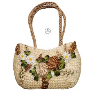 Pu&ograve; includere: Borsa a mano in paglia intrecciata con manico intrecciato. La borsa &egrave; decorata con margherite bianche, rose marroni e crema e foglie verdi. La borsa ha la scritta "KULTURA".