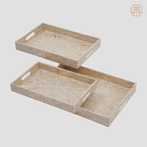 Puede incluir: Juego de tres bandejas rectangulares de diferentes tamaños. Las bandejas son de color beige claro con un diseño de patrón radial. Cada bandeja tiene un asa recortada a cada lado.