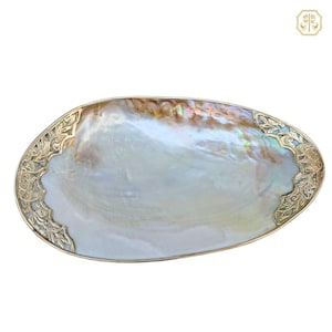 May include: An iridescent, oval decorative shell with a gold-coloured, ornate metal trim. The shell's interior has a pearlescent sheen, and the metal trim features floral and leaf designs. A luxurious accent piece.