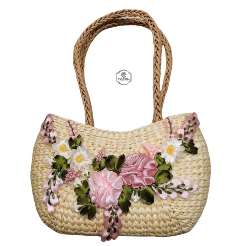 Pu&ograve; includere: Una borsa tote in paglia intrecciata con manico intrecciato. La borsa &egrave; decorata con rose in nastro di raso rosa, margherite bianche e foglie verdi. La borsa &egrave; di colore beige chiaro e ha un motivo floreale.