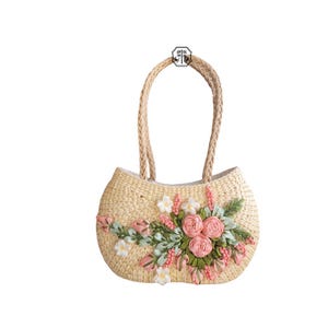 Pu&ograve; includere: Una borsa tote in paglia intrecciata con manici intrecciati. La borsa &egrave; decorata con una composizione floreale di fiori in tessuto rosa, bianchi e verdi. La borsa ha una forma arrotondata e un colore beige chiaro.