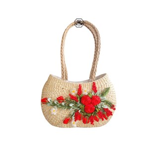 Pu&ograve; includere: Una borsa tote in paglia intrecciata con manici intrecciati. La borsa &egrave; decorata con un motivo floreale con rose rosse, fiori bianchi e foglie verdi. La borsa &egrave; di colore beige chiaro e ha una forma arrotondata.