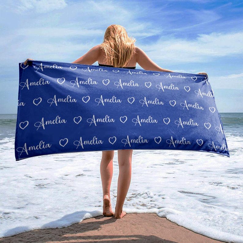 May include: A blue beach towel with the name "Amelia" repeated in white lettering with a heart between each name.