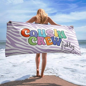 May include: A purple and white zebra patterned beach towel with the text "COUSIN CREW" in rainbow colors and the name "Ashley" in black script.