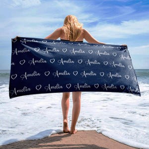 May include: A dark blue beach towel with the name "Amelia" repeated in white lettering with a heart between each name.