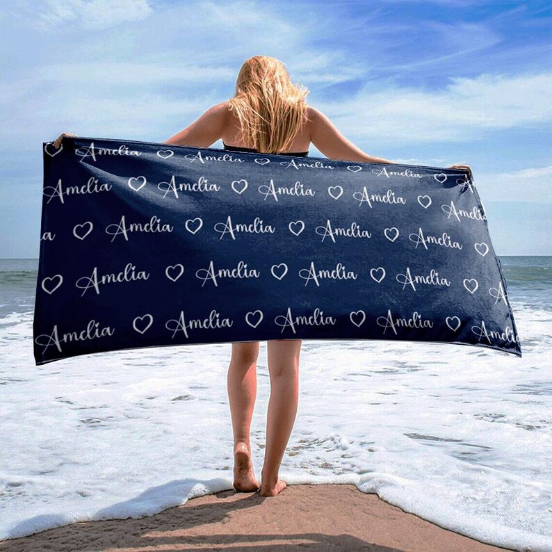 May include: A dark blue beach towel with the name "Amelia" repeated in white lettering with a heart between each name.