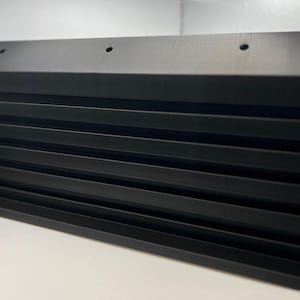 Puede incluir: Ventilación de plástico negro con lamas horizontales. La ventilación tiene una forma rectangular y está hecha de varias piezas.