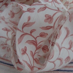 Peut inclure: Ruban en tissu blanc avec un motif floral rose. Le ruban est pli&eacute; et froiss&eacute;, montrant le motif en d&eacute;tail.