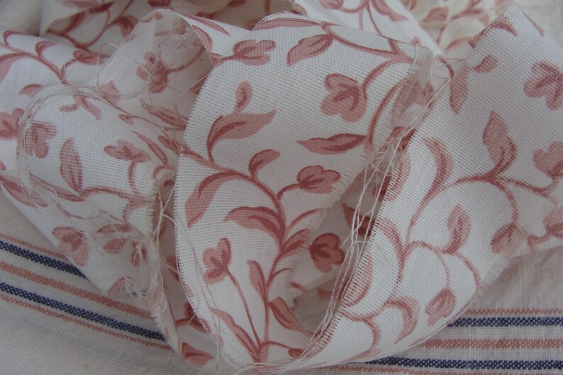 Peut inclure: Ruban en tissu blanc avec un motif floral rose. Le ruban est pli&eacute; et froiss&eacute;, montrant le motif en d&eacute;tail.