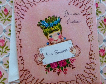 May include: A pink invitation card with a decorative border. The card features a cartoon girl with a flower crown holding a sign that says "to a shower". The text "You are Invited" is printed on the card.