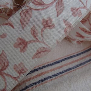 Peut inclure: Un gros plan sur un tissu blanc avec un motif floral rose. Le tissu est pli&eacute; sur lui-m&ecirc;me et a une texture subtile.