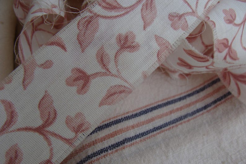 Peut inclure: Un gros plan sur un tissu blanc avec un motif floral rose. Le tissu est pli&eacute; sur lui-m&ecirc;me et a une texture subtile.