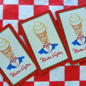 May include: Three playing cards with a red and white checkered background. Each card features a cartoon ice cream cone character wearing a blue suit and a bow tie. The text "Mister Softee" is printed on each card.