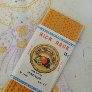 May include: A package of orange rick rack trim from Fruit of the Loom, size 13, containing 9 yards of 100% mercerized cotton. The packaging features a vintage design with the brand name and a fruit illustration.