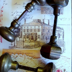 May include: Four antique brass door knobs with different styles and designs. The knobs are on a background of vintage paper with a house illustration and a lace doily.