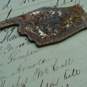 May include: A rusty metal hand pointing to the right. The hand is made of a thin metal sheet and has a rough, textured surface.