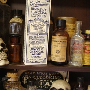 May include: A shelf with various glass bottles containing liquids. The bottles are labeled with text such as "Dr. Blumers High Grade Flavoring Extracts", "Eigenol Merck", and "Maylon". There is a skull on the left side of the shelf.