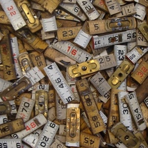 May include: A collection of vintage wooden rulers with various measurements, including inches and centimeters. The rulers are in various shades of brown and white, with some showing signs of wear and tear.