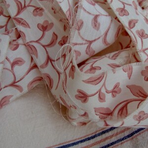 Peut inclure: Un gros plan sur un ruban en tissu floral rose et blanc. Le ruban est pli&eacute; et superpos&eacute;, montrant le motif floral complexe.