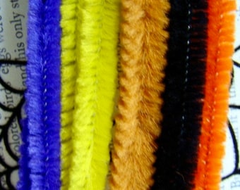 May include: Close-up of colorful pipe cleaners in blue, yellow, orange, black, and red-orange. The fuzzy texture of the pipe cleaners is visible, with each color forming a vertical stripe. These craft supplies are ideal for various DIY projects.