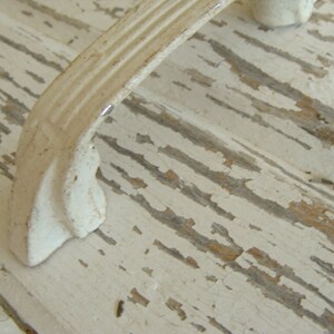 May include: White painted wooden surface with a white metal handle. The paint is chipped and worn, giving the surface a rustic look.