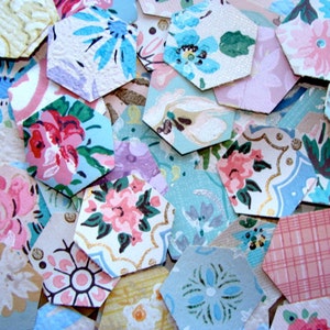 May include: A collection of hexagon-shaped paper scraps with various floral and geometric patterns in shades of pink, blue, green, and white.
