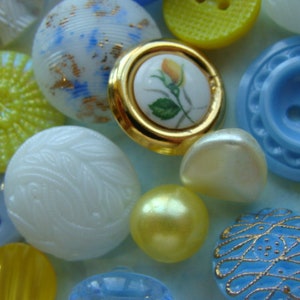 May include: Assortment of colorful buttons in various shapes and sizes, including white, blue, yellow, and floral designs.
