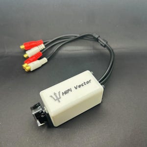 Könnte beinhalten: Ein weißes HiFi Vector Audiogerät mit schwarzen Kabeln und roten und weißen Cinch-Anschlüssen. Das Gerät hat einen schwarzen Knopf und den Text "HiFi Vector" auf der Vorderseite.