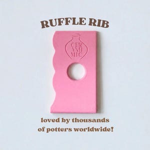 May include: A pink pottery rib tool with a wavy edge and a circular cutout. The tool features an embossed vase icon with the text CER ANH MIC. Above the tool is the text RUFFLE RIB, and below is the text loved by thousands of potters worldwide!