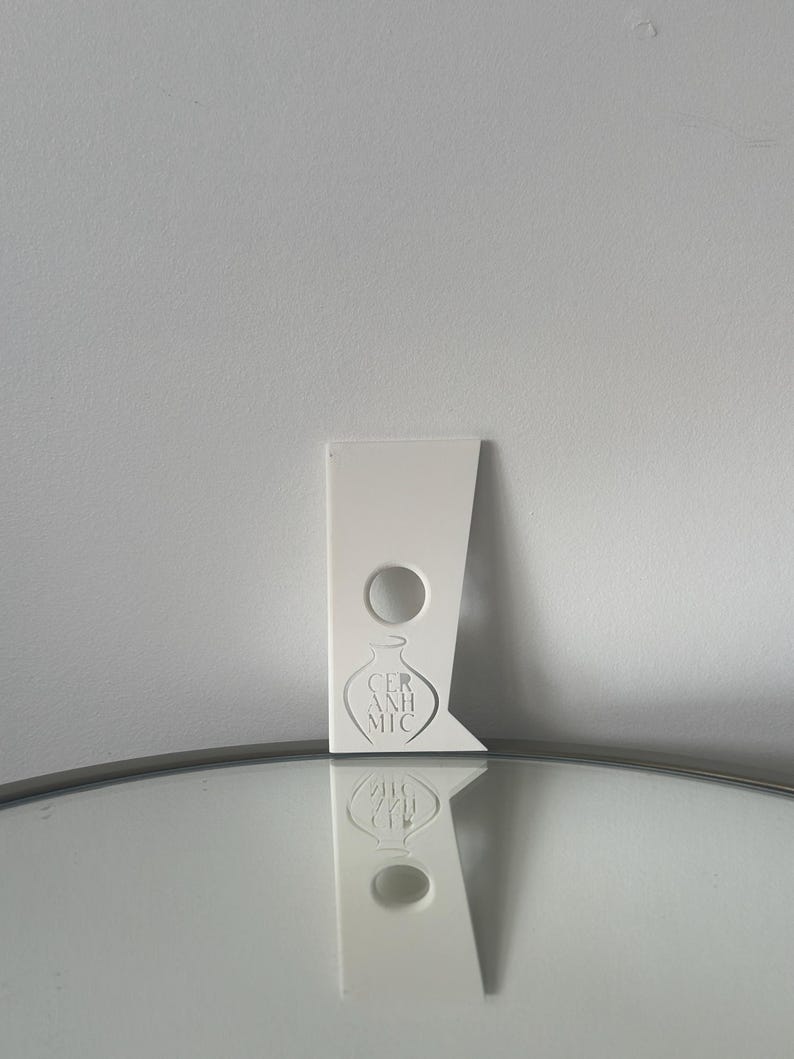 May include: White ceramic pottery tool with a hole in the centre and the text "CERAMIC" printed on the bottom.
